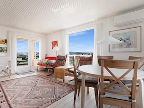 A spacious living area with a large window, a red sofa, a wooden dining table, and a patterned rug. - 5 Star Holiday Home in Lokken (Lokken)