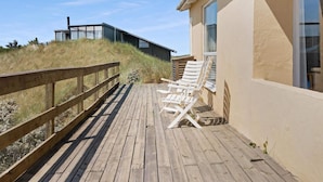 A wooden deck with lounge chairs and a view of a modern building with large windows.