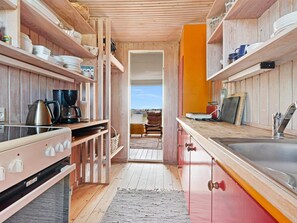 A modern kitchen with wooden cabinetry, a stainless steel sink, and a view to the outside. - 5 Star Holiday Home in Lokken (Lokken)