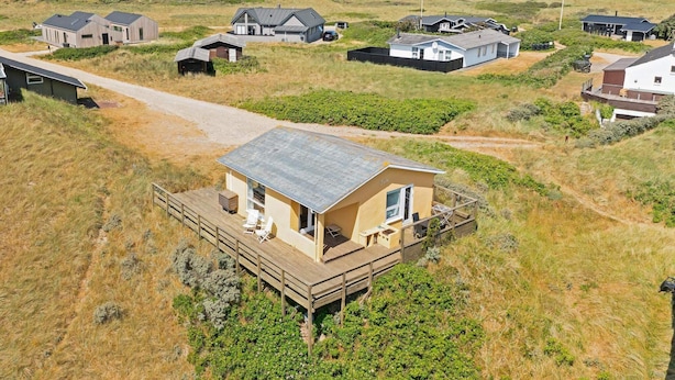 A coastal area with multiple houses, including a prominent house with a deck and a view of the sea.