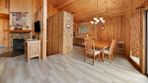 Interior d'una cabana de fusta amb menjador, cuina i llar de foc.