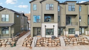 A modern multi-story residential building with a stone foundation and a central fireplace. - The Foxtrot at Mesa Arch Lane (Mountain Green)