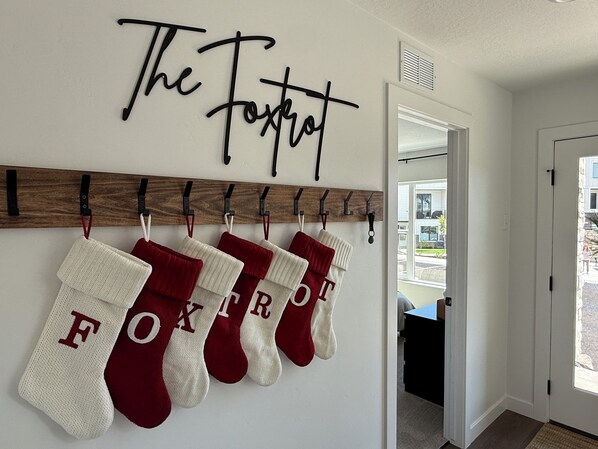 A hallway with a wall-mounted sign reading "The Foxrat" and a row of stockings with letters.