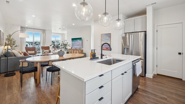 A modern kitchen with a central island, white cabinetry, and stainless steel appliances. - The Foxtrot at Mesa Arch Lane (Mountain Green)