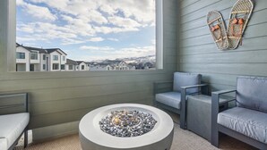 A modern balcony with a fire pit, seating, and a view of a residential area. - The Foxtrot at Mesa Arch Lane (Mountain Green)