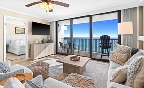 A spacious balcony with a view of the ocean, a seating area with a coffee table, and a TV mounted on the wall. - One Seagrove Place 0707 (Santa Rosa Beach)