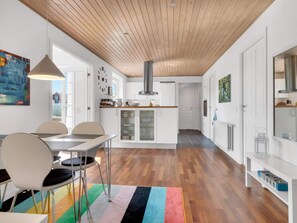 A modern kitchen with wooden flooring, white cabinetry, and a central island.