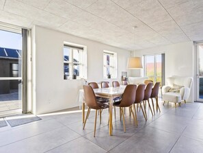 A modern dining area with a large table, chairs, and a lamp. - 5 Star Holiday Home in Lokken (Lokken)