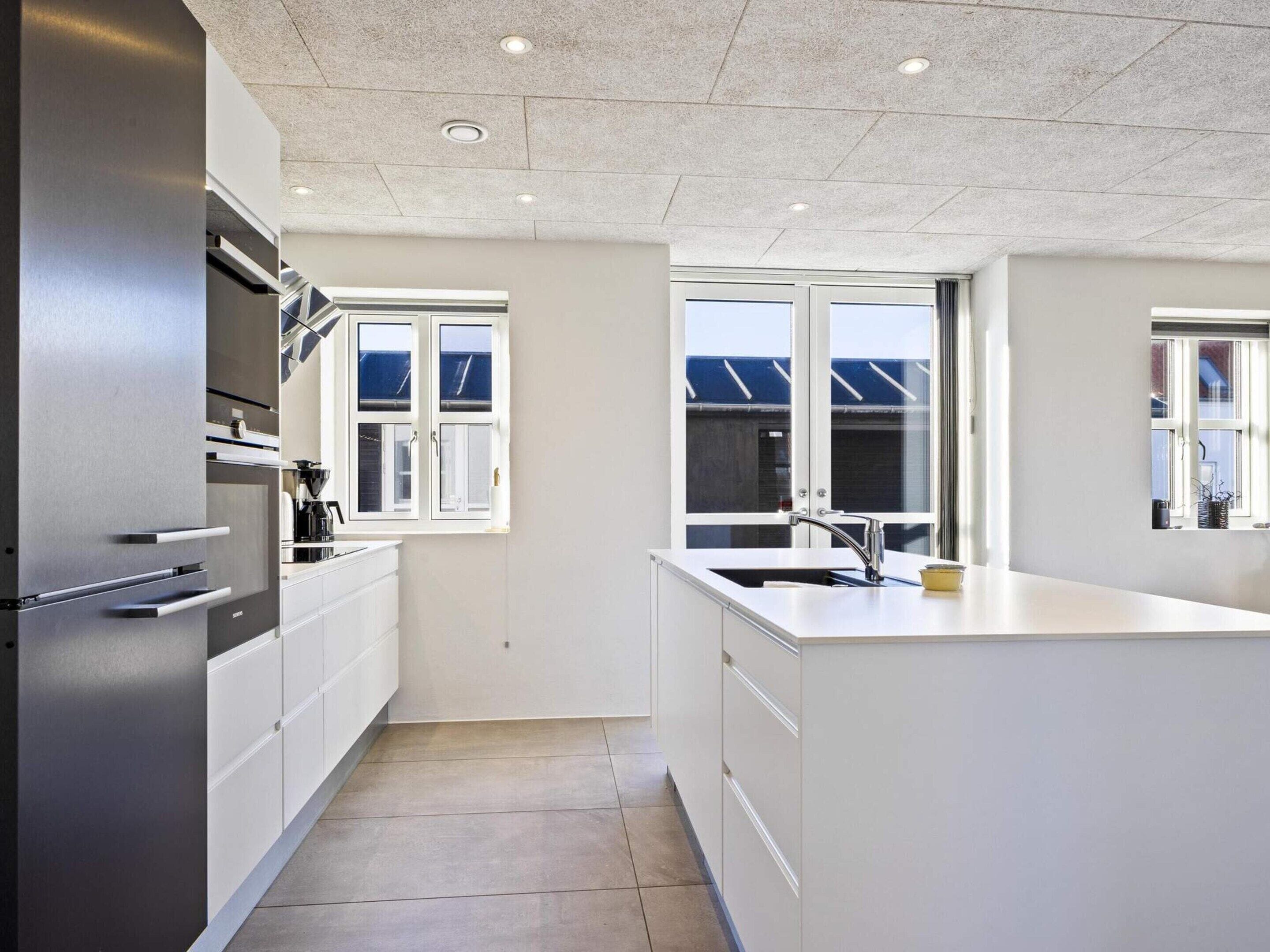A modern kitchen with white cabinetry, stainless steel appliances, and a large window providing natural light.