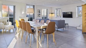 A modern living room with a dining table, chairs, a sofa, and a TV. - 5 Star Holiday Home in Lokken (Lokken)