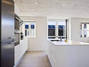 A modern kitchen with white cabinetry, stainless steel appliances, and a large window providing natural light.