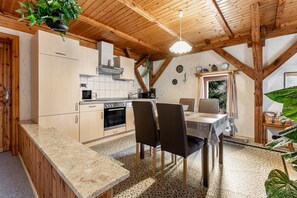 A kitchen with wooden beams, a dining table with chairs, and a hanging plant. - Apartment '1' with Shared Terrace and Wi-Fi (Ostrohe)