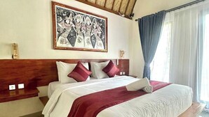 Quarto de hotel com uma cama grande, cabeceira de madeira, colcha vermelha e branca e uma obra de arte emoldurada na parede.
