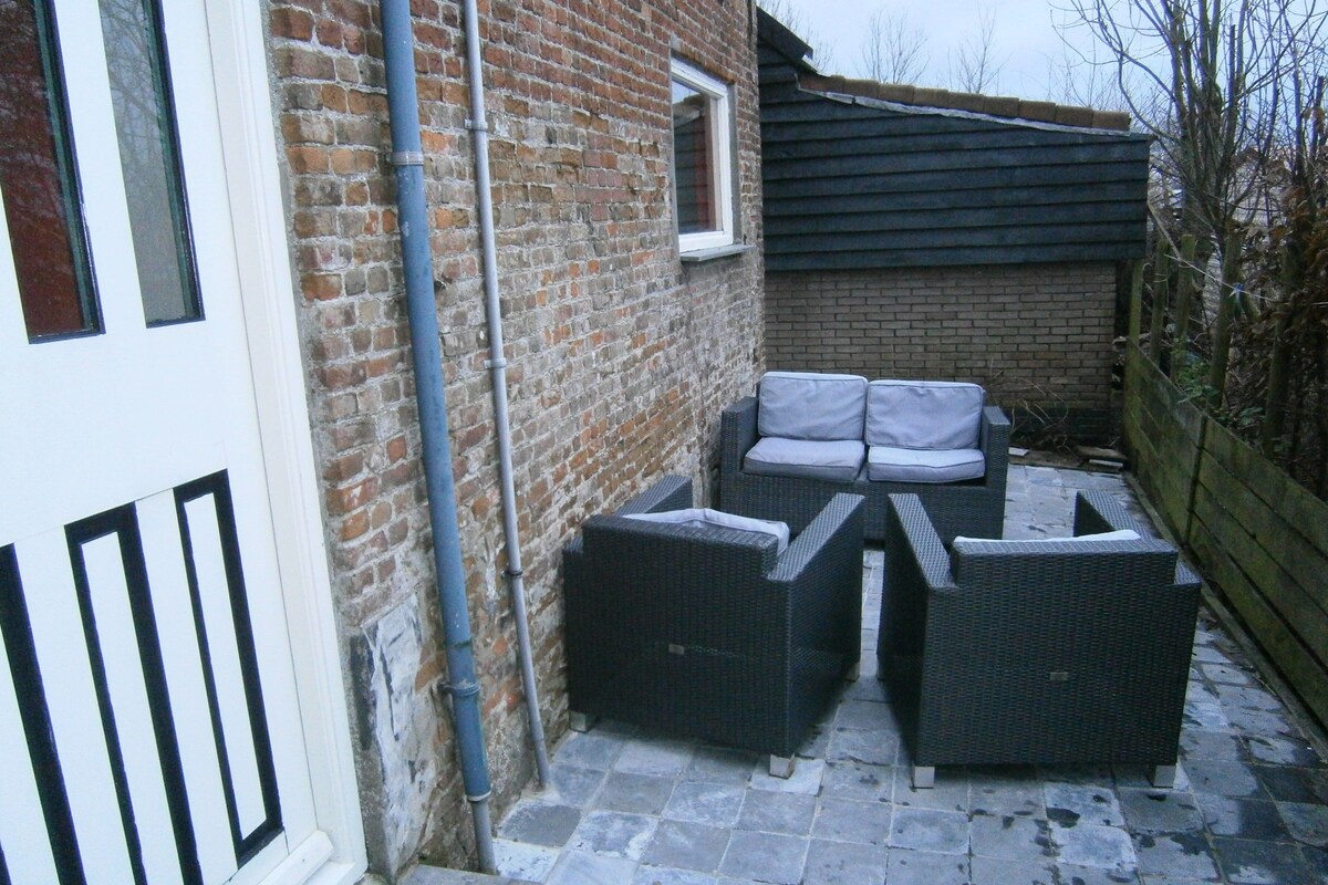 A courtyard with a brick wall, a white door, and outdoor furniture.
