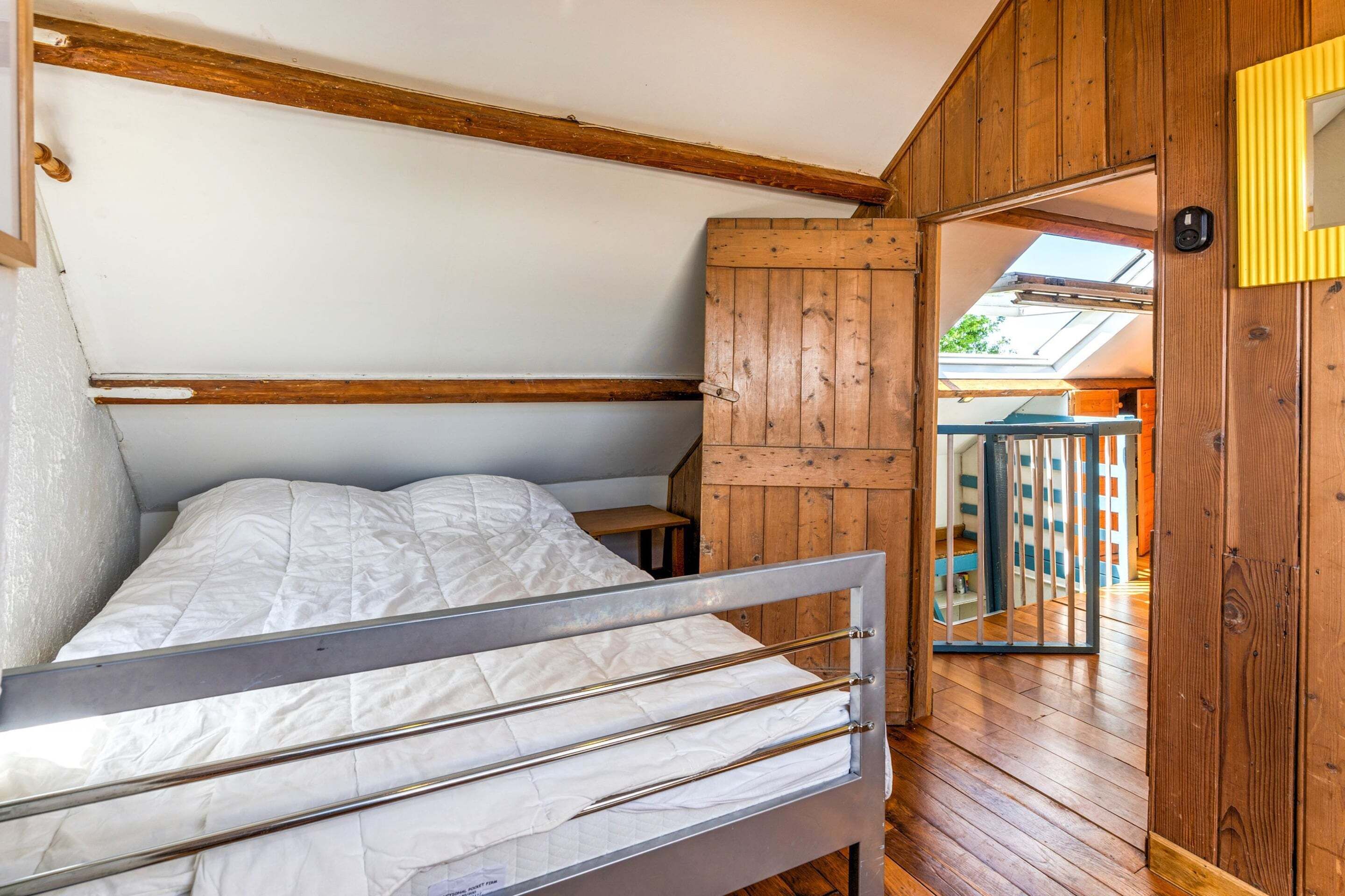 Une petite pièce en bois, avec un lit superposé, une armoire en bois et une vue sur l’extérieur grâce à une porte vitrée.