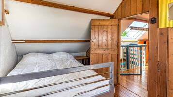 Une petite pièce en bois, avec un lit superposé, une armoire en bois et une vue sur l’extérieur grâce à une porte vitrée.