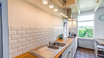Une cuisine moderne avec des carreaux de céramique blancs disposés en motif métro, un évier en acier inoxydable et une fenêtre donnant sur un paysage verdoyant.