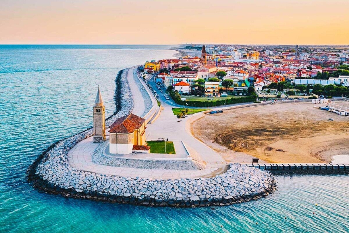 Une ville côtière qui se distingue par une église imposante, une plage et une digue rocheuse.