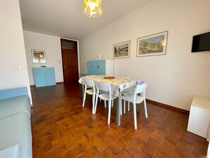 Een eetruimte met een tafel, stoelen en een blauwe kast.