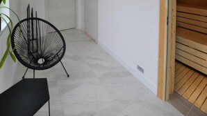 Ein Flur mit einer weißen Tür, einem schwarzen Stuhl und einer hölzernen Bank.