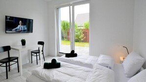 Ein modernes Schlafzimmer mit zwei Betten, einem Schreibtisch und einem Fernseher.
