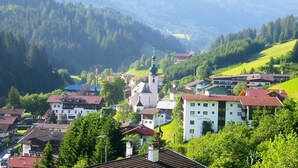 En stad med olika byggnader, inklusive ett pensionat med café som heter ”Sun Valley”, omgiven av gröna kullar och berg.