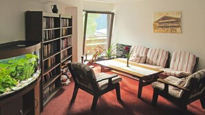 Een woonkamer met een boekenkast, een aquarium, een bank en een salontafel.