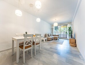 A modern living room with a dining area, featuring a sofa, a coffee table, and a dining table with chairs. - Faro's Malaga Citylights - Amazing Roof Terrace (Málaga)