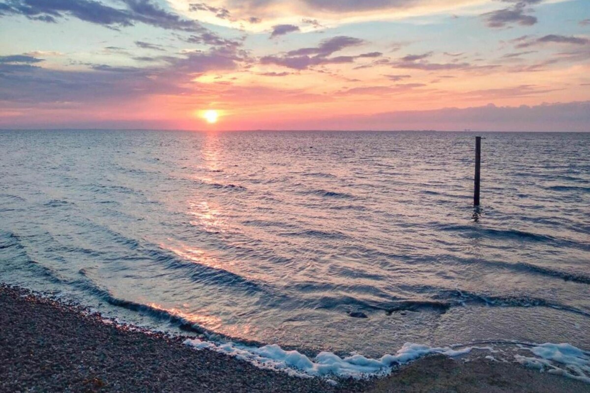 Un atardecer sobre un mar tranquilo con olas suaves y cielo despejado.