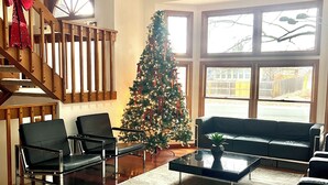 Un salón espacioso con una escalera de madera, un árbol de Navidad y un gran ventanal.