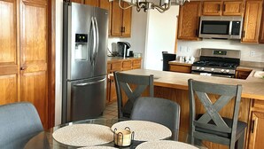 Una cocina moderna con armarios de madera, electrodomésticos de acero inoxidable y una mesa de comedor de vidrio con individuales tejidos.