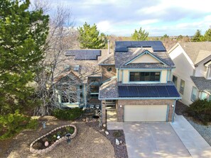 A residential house with solar panels, a garage, and a landscaped garden.