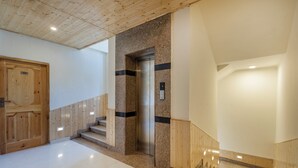 A modern interior with a wooden door labeled '304', a staircase with wooden railings, and a central elevator. - Treebo Premium Silverstone Resort With Mountain Valley View (Manali)