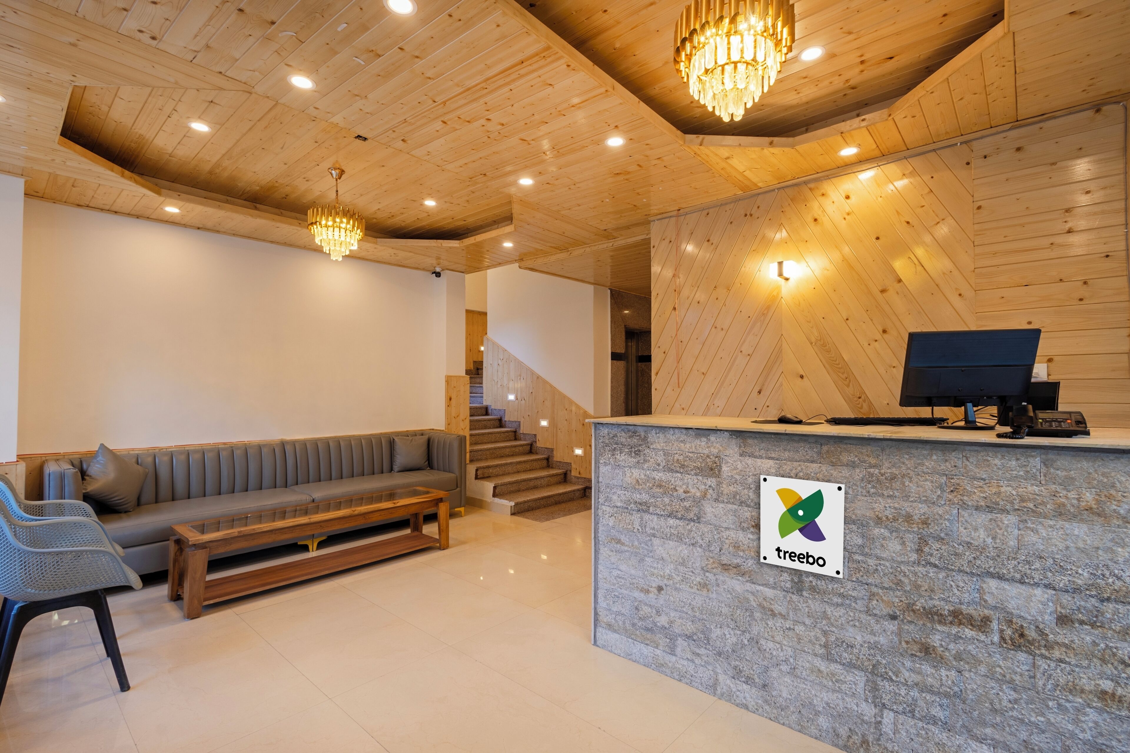 A reception area with a wooden reception desk, a grey sofa, and a staircase leading to upper floors.
