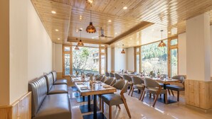 A spacious dining area with wooden ceiling, large windows, and modern furniture. - Treebo Premium Silverstone Resort With Mountain Valley View (Manali)