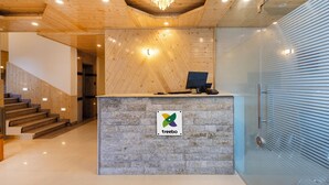 A reception desk with a wooden finish, a chandelier, and a logo. - Treebo Premium Silverstone Resort With Mountain Valley View (Manali)
