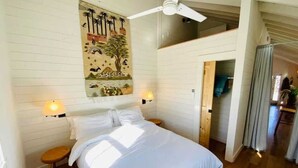 A bedroom with a bed, two bedside tables, a ceiling fan, and a wall-mounted lamp. - Aftonshire Cottage - Heart of Afton's Wine Region (Afton)