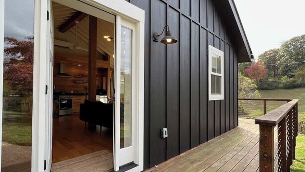 A modern building with a wooden deck, a sliding glass door entrance, and a small window. - Aftonshire Cottage - Heart of Afton's Wine Region (Afton)