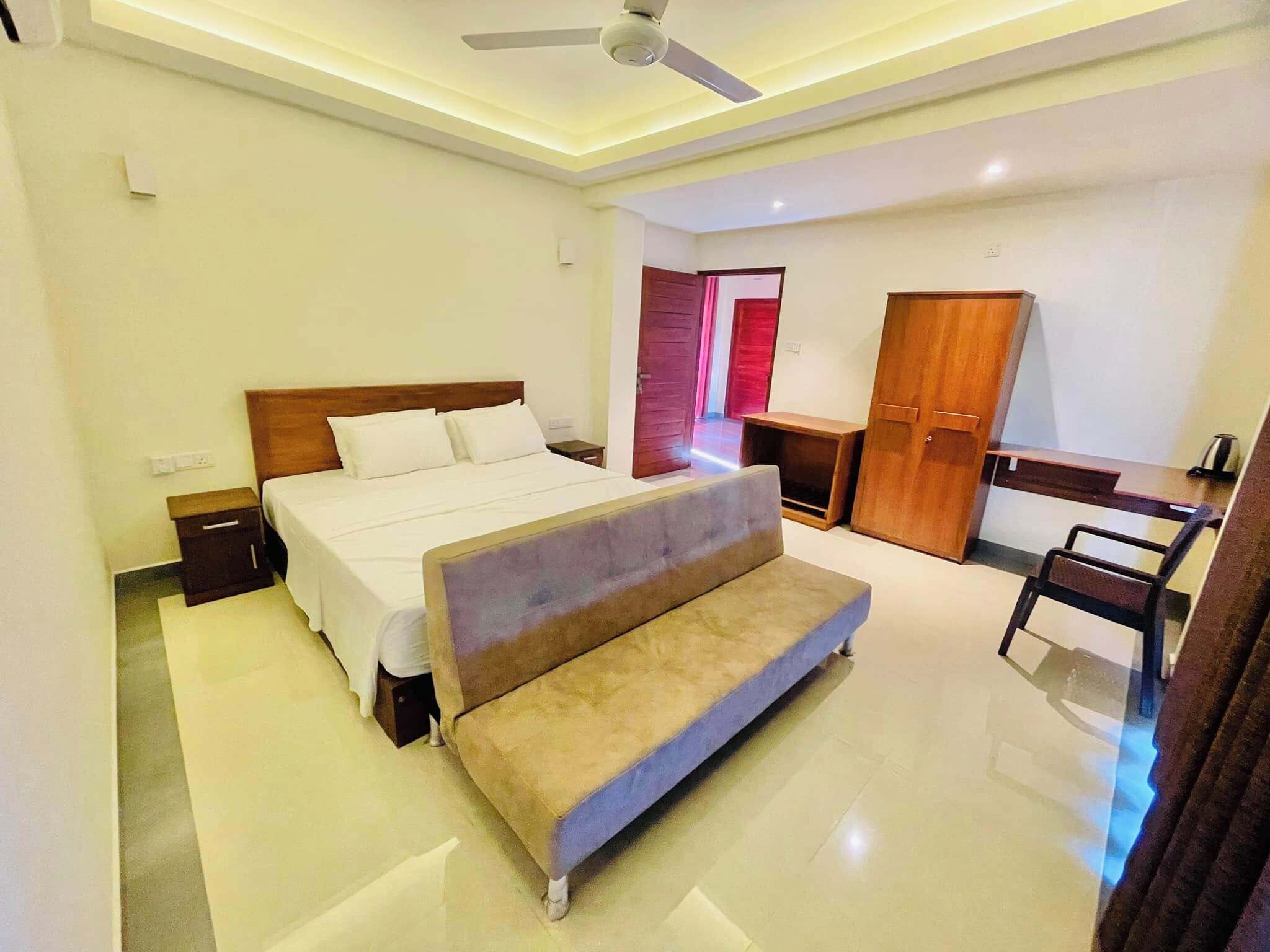 Um quarto moderno com uma cama, um banco, uma escrivaninha e um guarda-roupa.