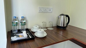 A hotel room with a wooden table, a tray with water bottles, cups, and a kettle. - Located in Galle, 2.5 km from  Beach, Fortwill City Hotel provide accommodation  (Galle)
