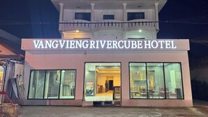 The exterior of Vang Vieng Rivercove Hotel with a prominent sign, large windows, and a balcony. - Vang Vieng Rivercube Hotel (Vang Vieng)