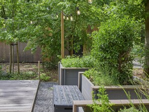 Escape to a serene garden oasis with lush vegetation and a tranquil wooden deck.