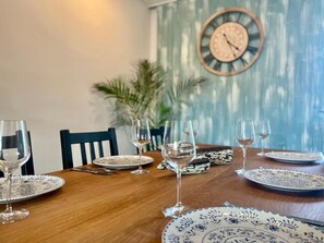 Een eettafel gedekt met borden, glazen en bestek, met een klok aan de muur op de achtergrond.