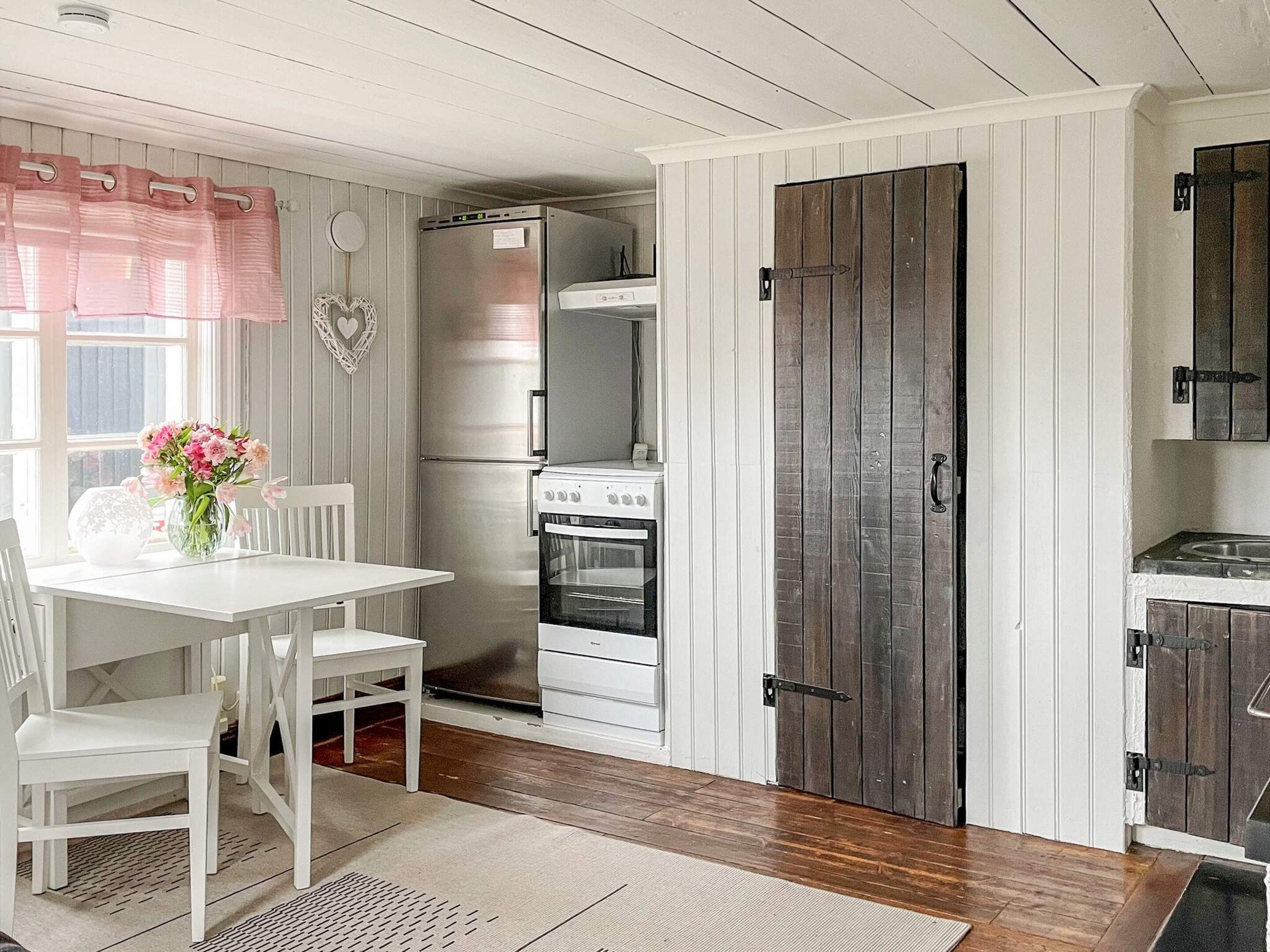 A compact kitchen with a refrigerator, oven, and a wooden door.