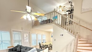 A spacious living room with a large sectional sofa, a dining area, and a staircase leading to an upper level. - Waterfront 3BR 2BA Home near Galveston, Kemah, NASA, NRG, Rodeo, Houston (La Porte)