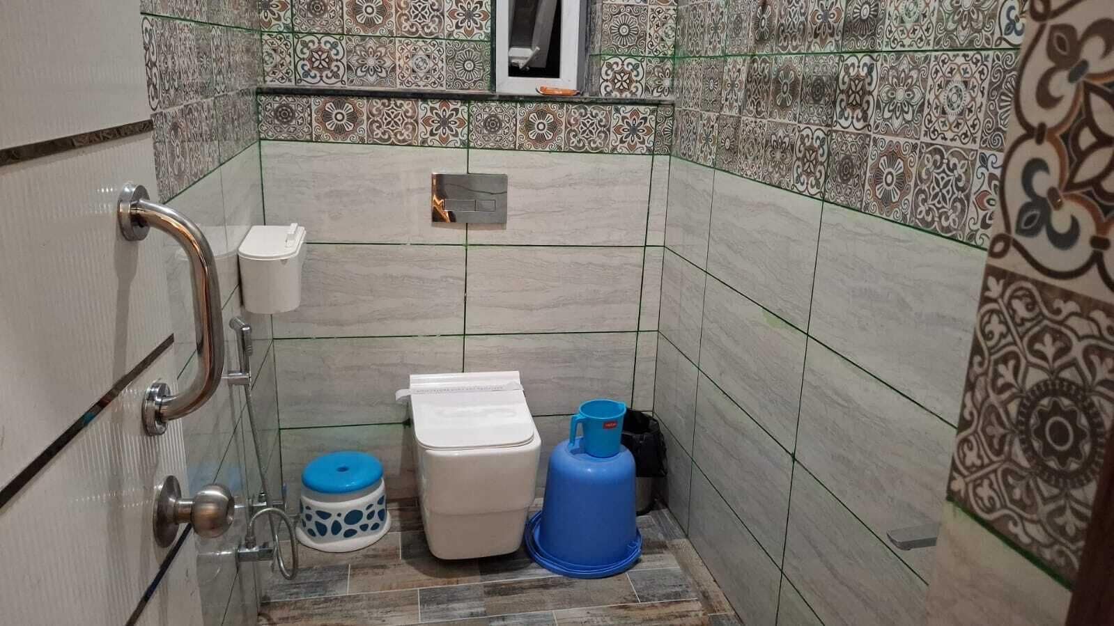 A bathroom with a shower, toilet, and storage bins.