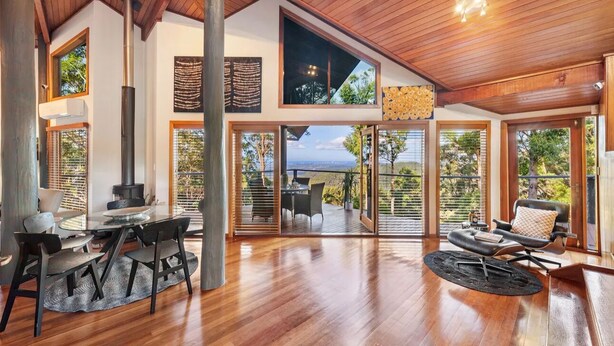 A spacious living area with a large wooden ceiling, a central fireplace, and a view of the outdoors through large windows. - Cosy Mountain house w/fire and pool on Tamborine Mountain! (Tamborine Mountain)