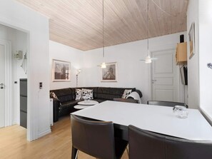 A modern kitchen with a white countertop, black chairs, and a wooden ceiling.