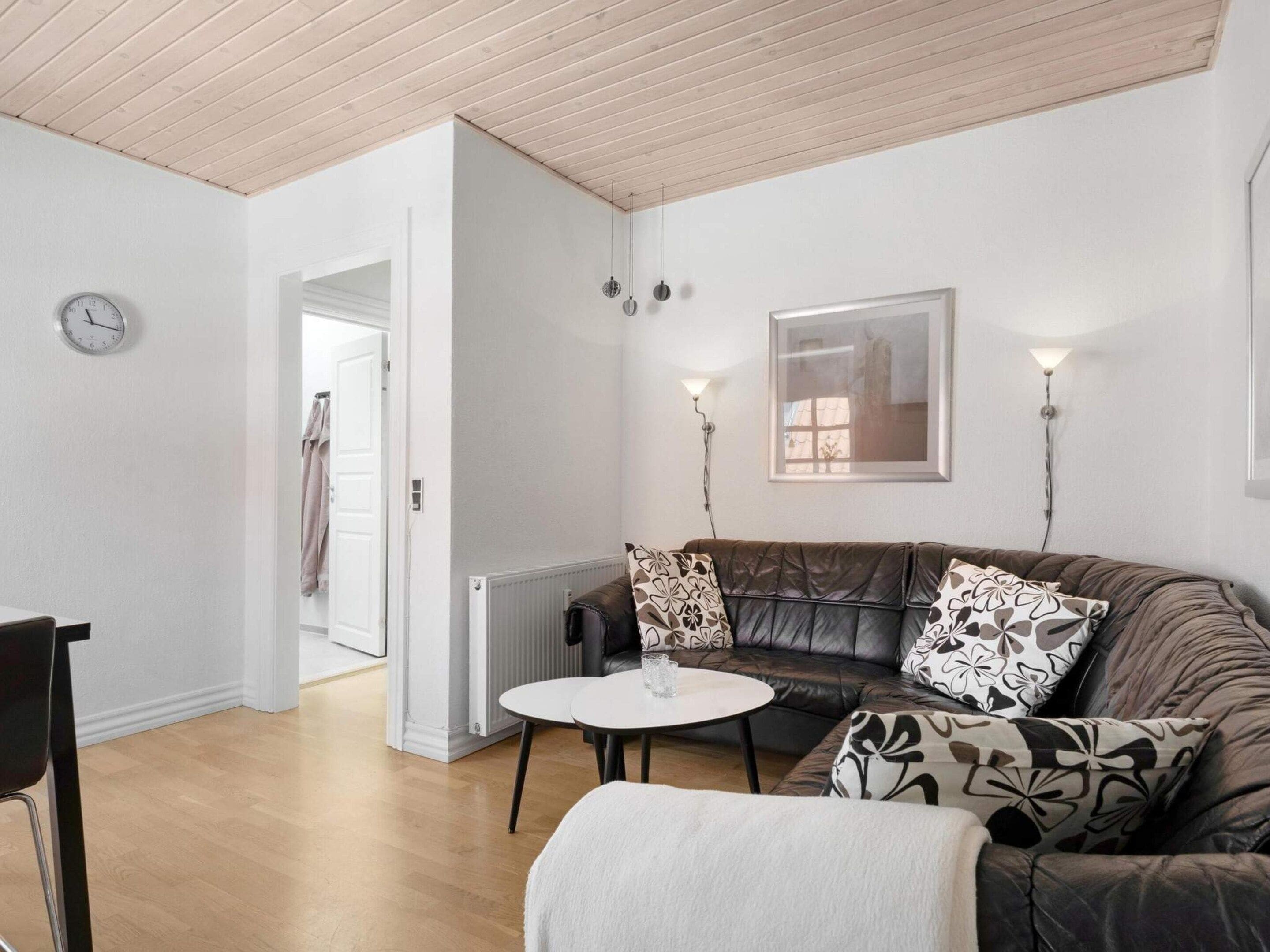 A modern living room with a leather sofa, a round coffee table, and a clock on the wall.
