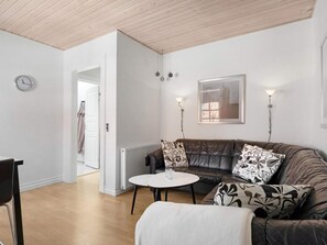 Un salon moderne avec un canapé en cuir, une table basse ronde et une horloge au mur.